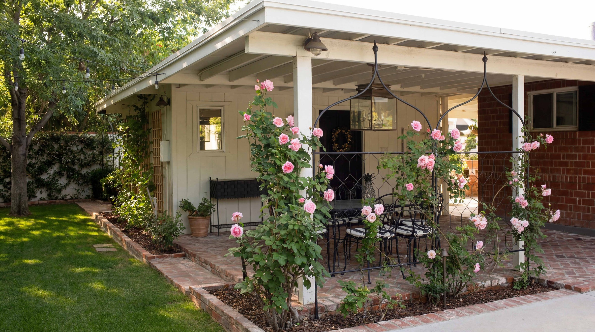 Patio with Agriframes garden screens decorated with pink flowers, surrounded by greenery.