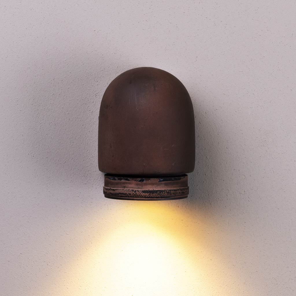 Cylindrical wall light fixture emitting a warm glow on a plain background