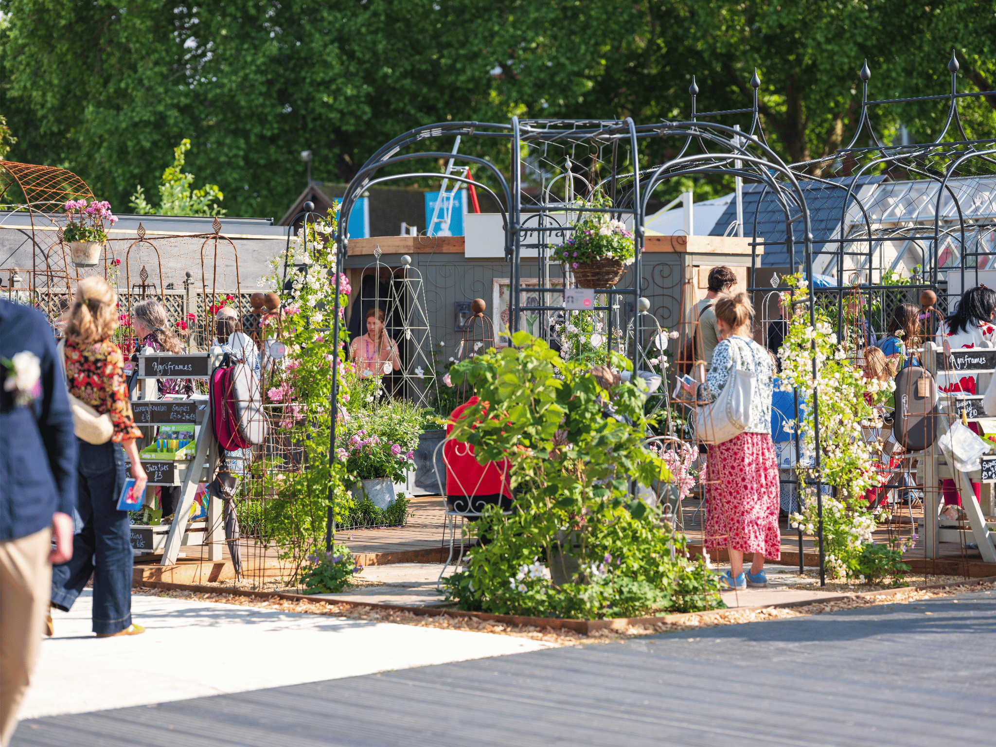 Garden show with people and plants, featuring a greenhouse and various plants on display.