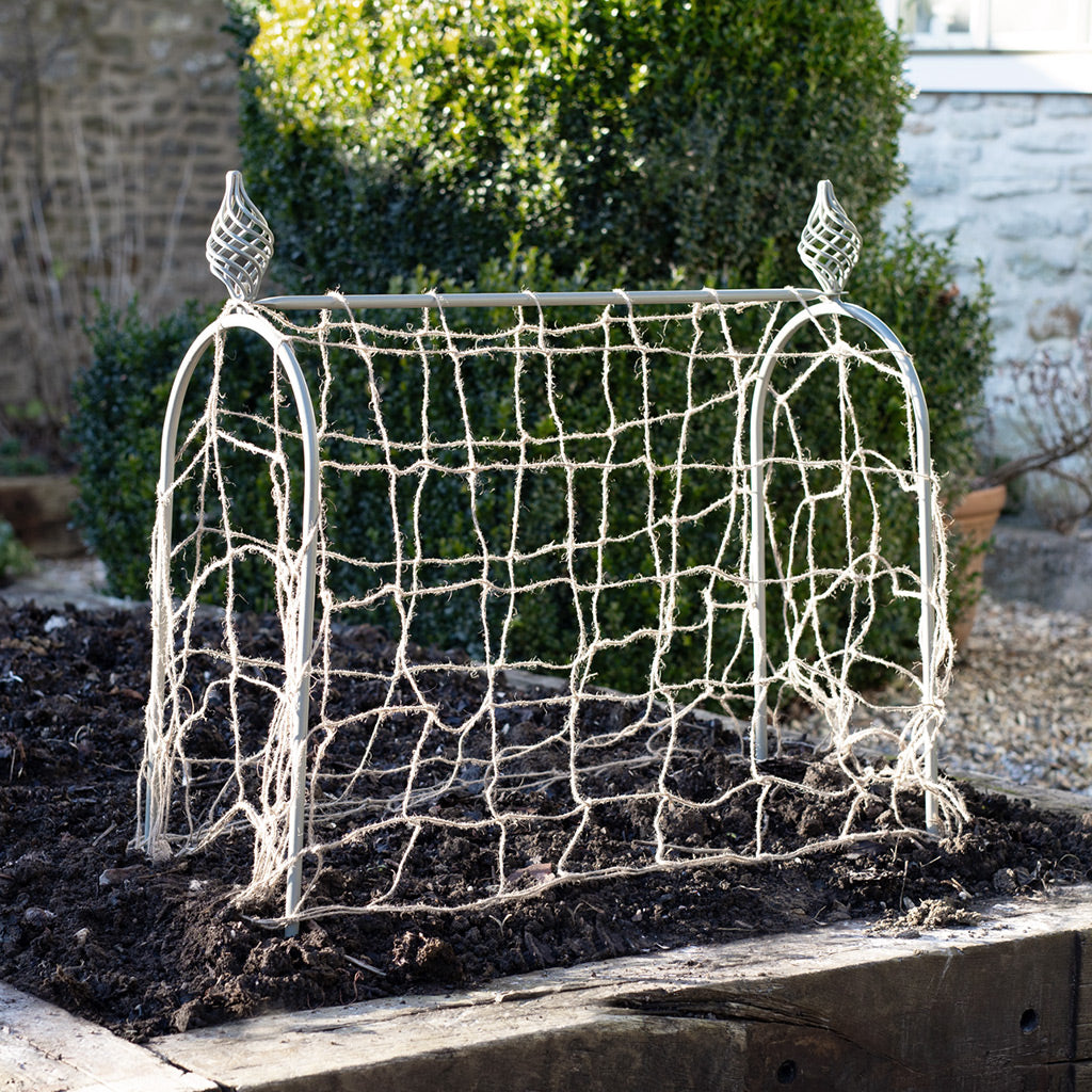 Decorative wire mesh structure with decorative elements on a stone surface.