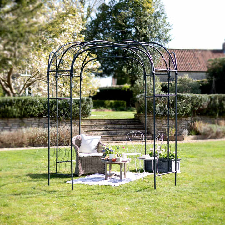 Garden arch with outdoor furniture on a grassy area