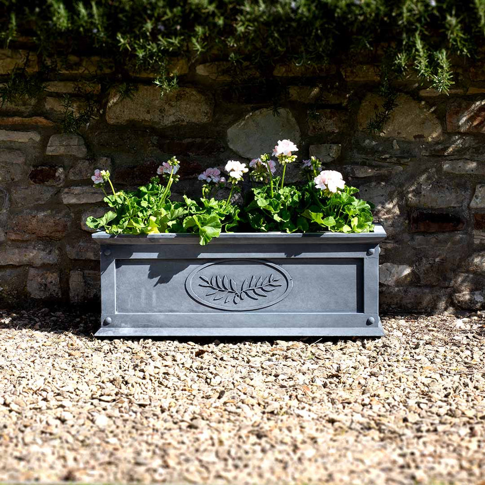 Decorative planter with flowers against a stone wall