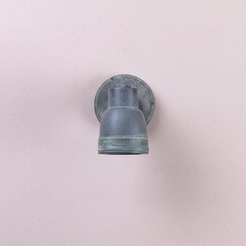 Agriframes atworth outdoor wall lamp in an old iron finish with its bulb unlit on a neutral wall. 