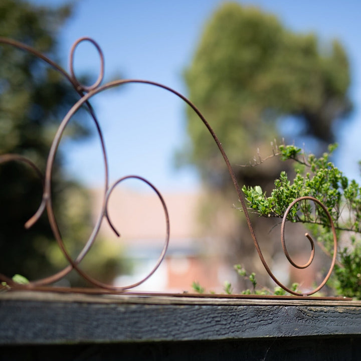 Decorative metal Agriframes Elegance Fence Top Trellis with greenery in the background