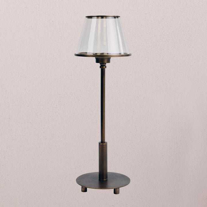 Decorative floor lamp with a clear glass shade on a light pink background