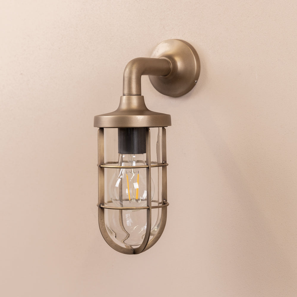 Angled image of the Agriframes Exmouth Outdoor Wall Lamp in a Brass finish with its bulb switched off, mounted on a neutral background. 