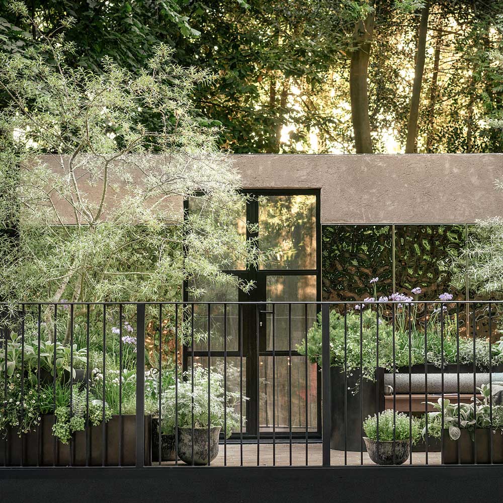 Modern house with greenery and a fence in a forest setting