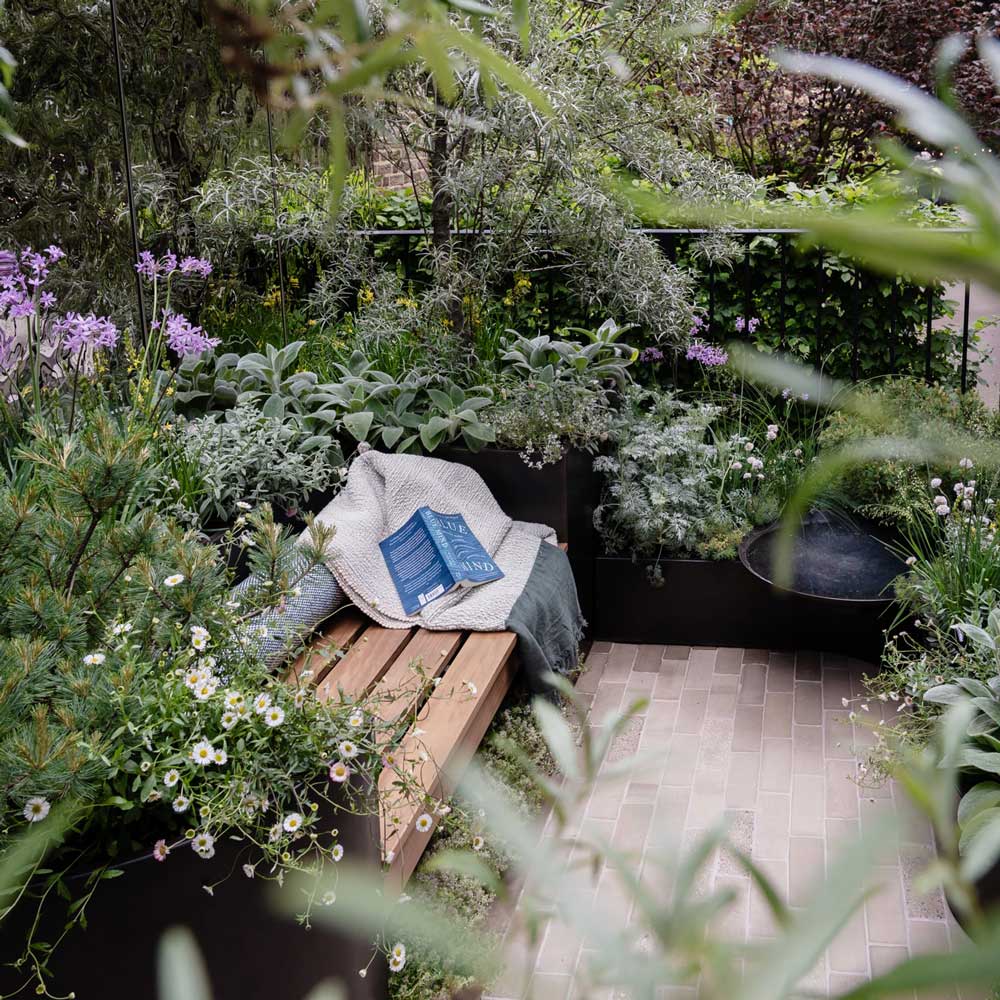 Garden setting with a wooden bench, plants, and a book.