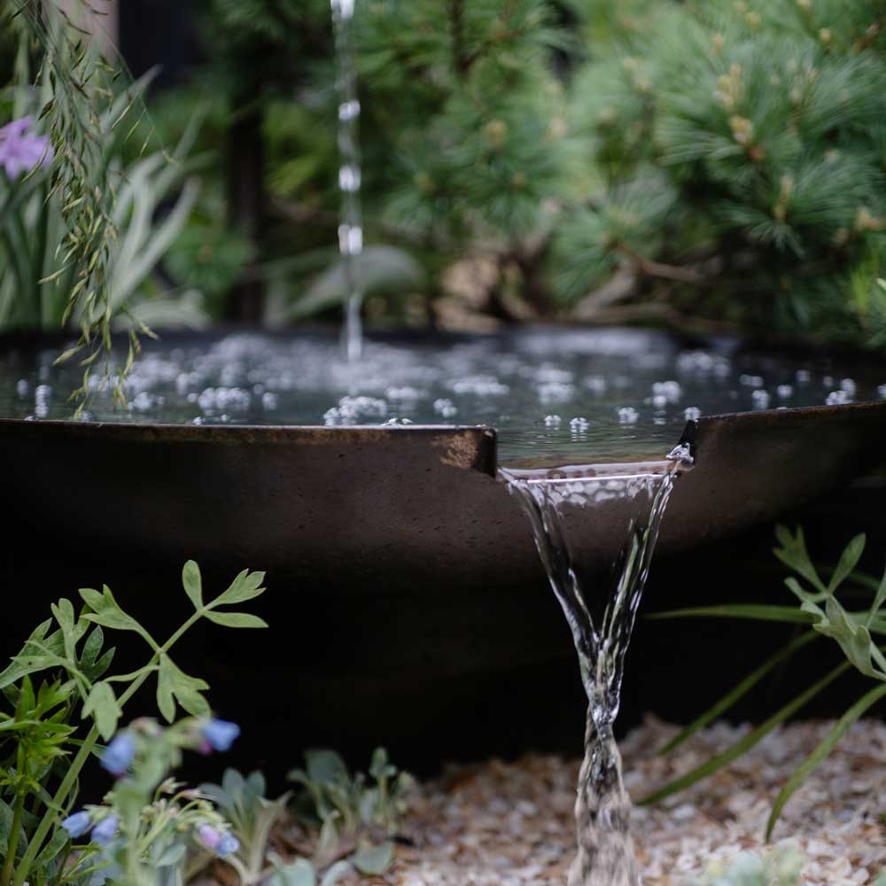 Water feature in a garden with plants and gravel