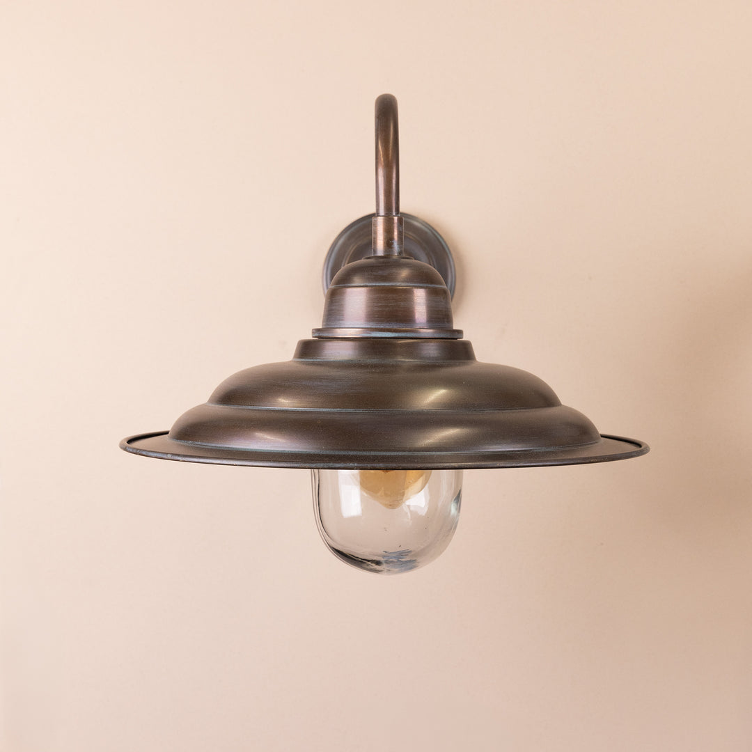 Front on image of the Agriframes Bucklebury Outdoor Wall Lamp in a Copper Patina finish with a switched off bulb mounted on a neutral-coloured wall. 