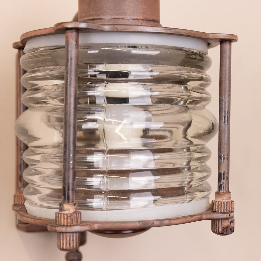 Closeup image of the Agriframes Frome Outdoor Wall Lamp in a Rust finish with its bulb switched off, highlighting the lamp's glass section.