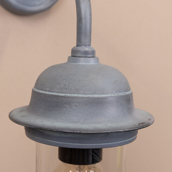 Closeup image of the Agriframes Pewsey Outdoor Wall Lamp in an Old Iron finish with its bulb switched off, mounted on a neutral background. 