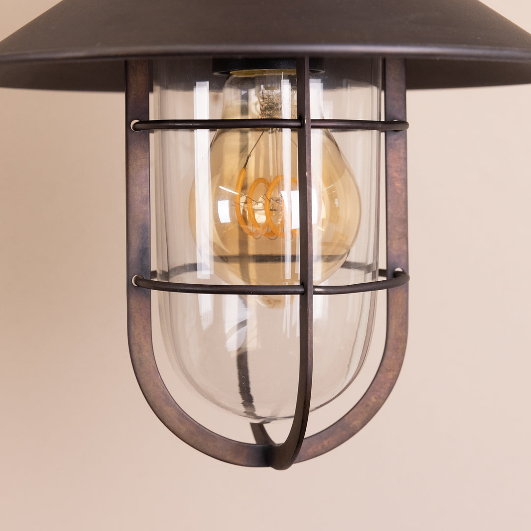 Closeup image of the bulb and glass casing of the Agriframes Sidmouth Outdoor Wall Lamp in a Bronze finish with its bulb switched off.