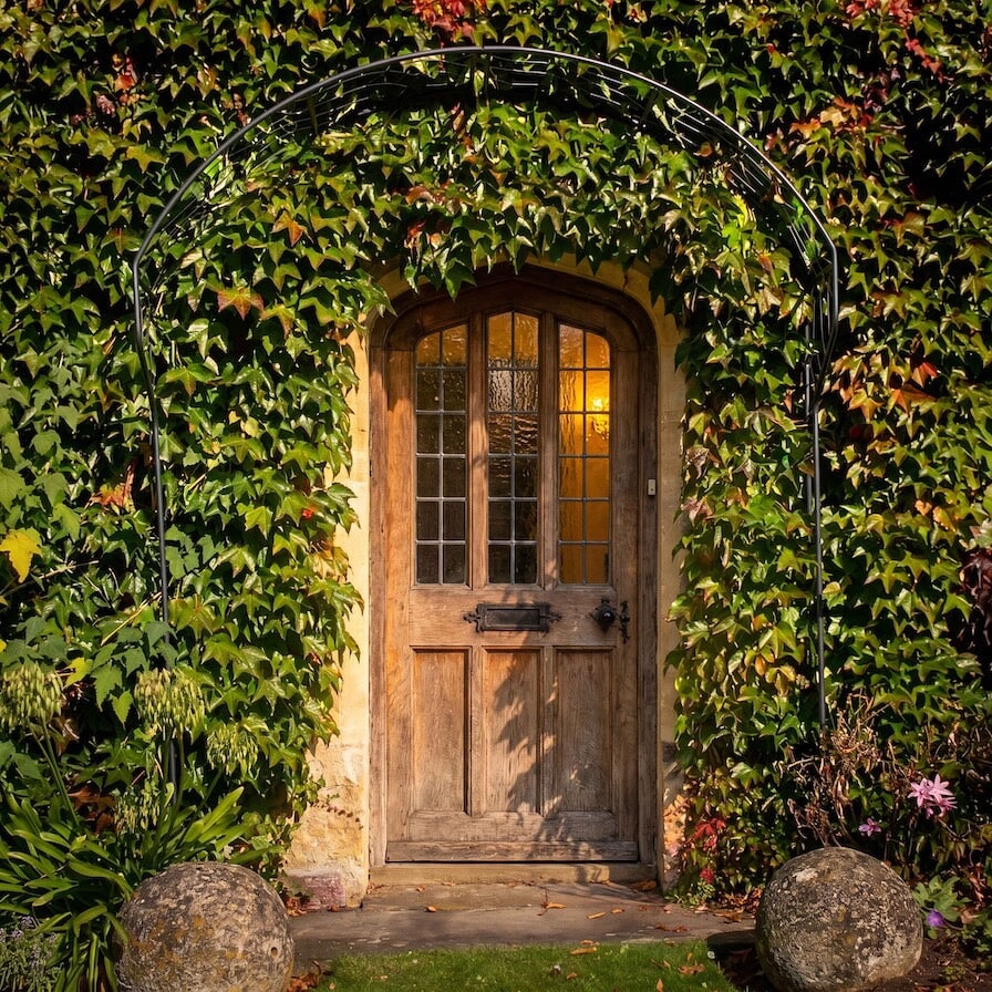 Agriframes Edwardian Portico installed across a wooden front door of a house covered in climbing ivy.