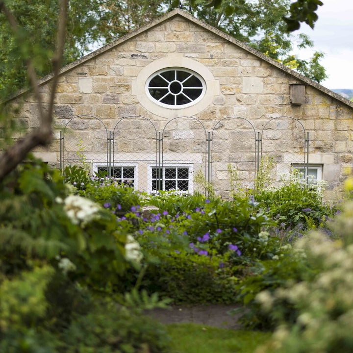 Several agriframes elegance round screens linked togehter between a flowerbed and a house