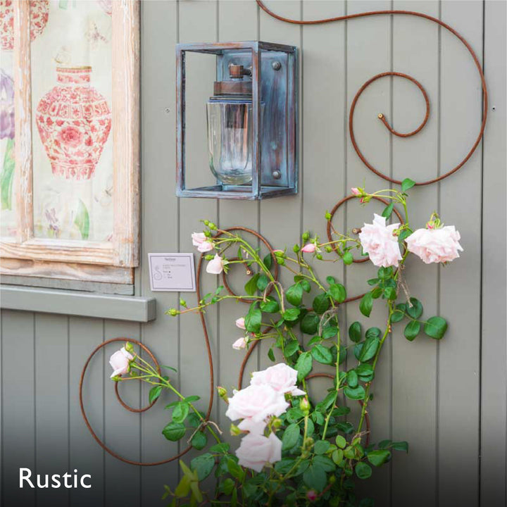 Decorative elegance wall scroll trellis with floral climbing plant, lantern, and rustic metal art on a wooden panel background.