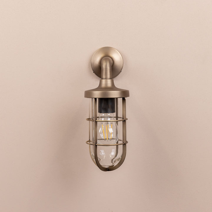 Front on image of the Agriframes Exmouth Outdoor Wall Lamp in a Brass finish with its bulb switched off, mounted on a neutral background. 