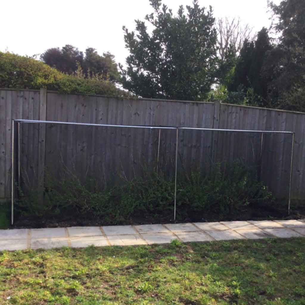 Knowle Nets Aluminium Low Fruit Cage panels rested against a wood fence in a garden