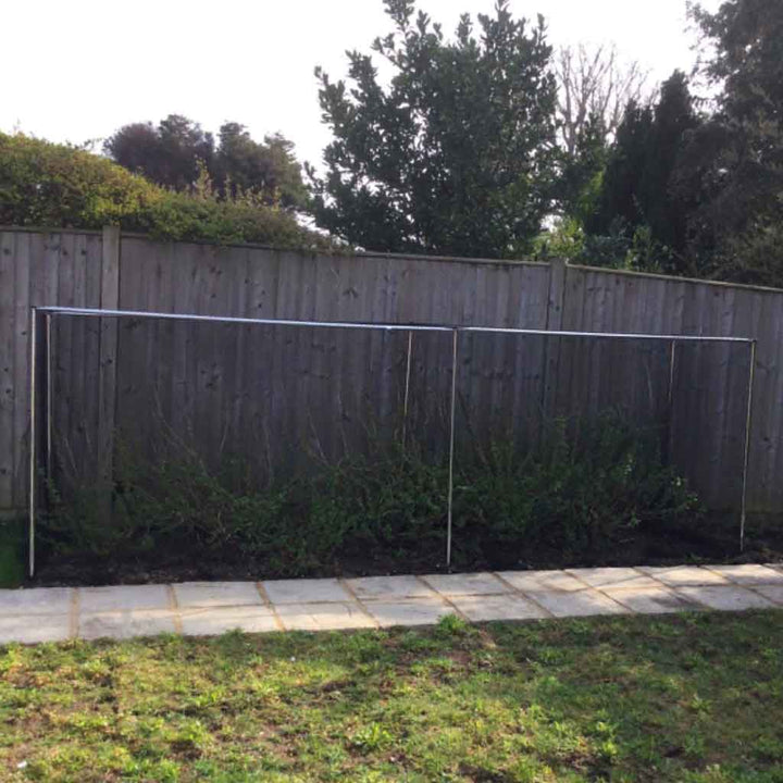 Knowle Nets Aluminium Low Fruit Cage panels rested against a wood fence in a garden