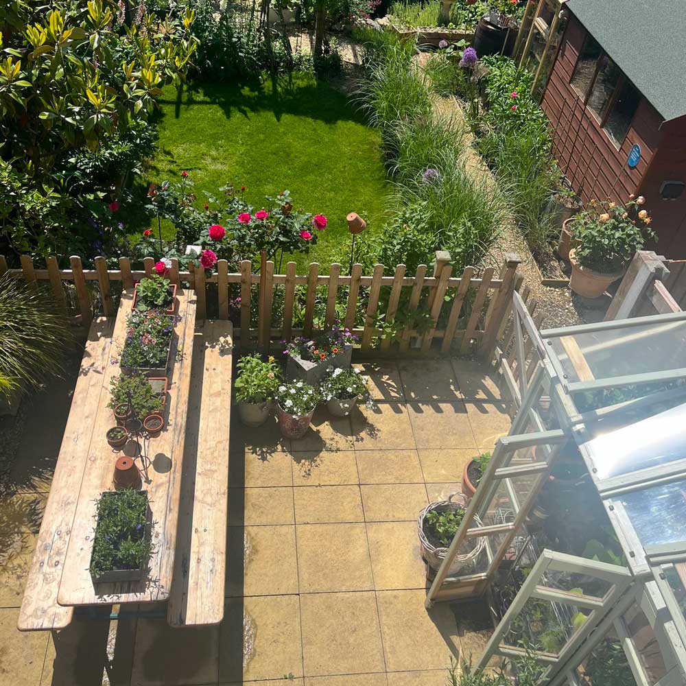 Garden scene with a wooden table, potted plants, and a wooden fence.