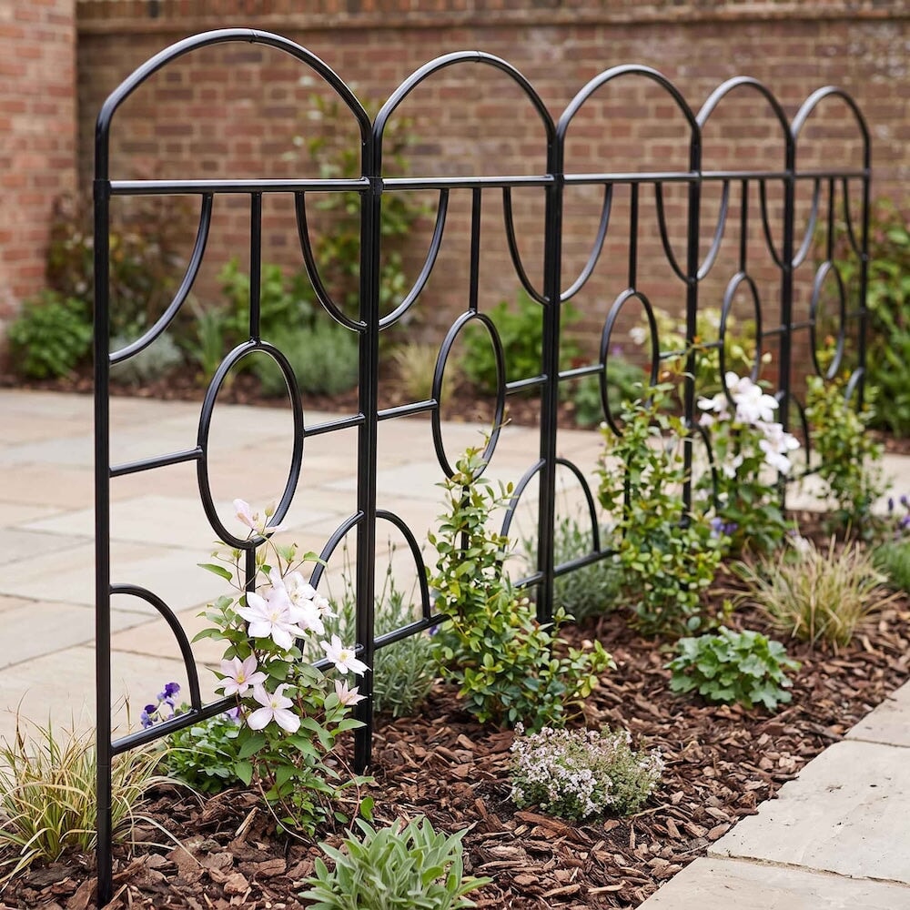 Several agriframes georgian monet screents linked together in a narrow flowerbed with different types of flower growing up the frames