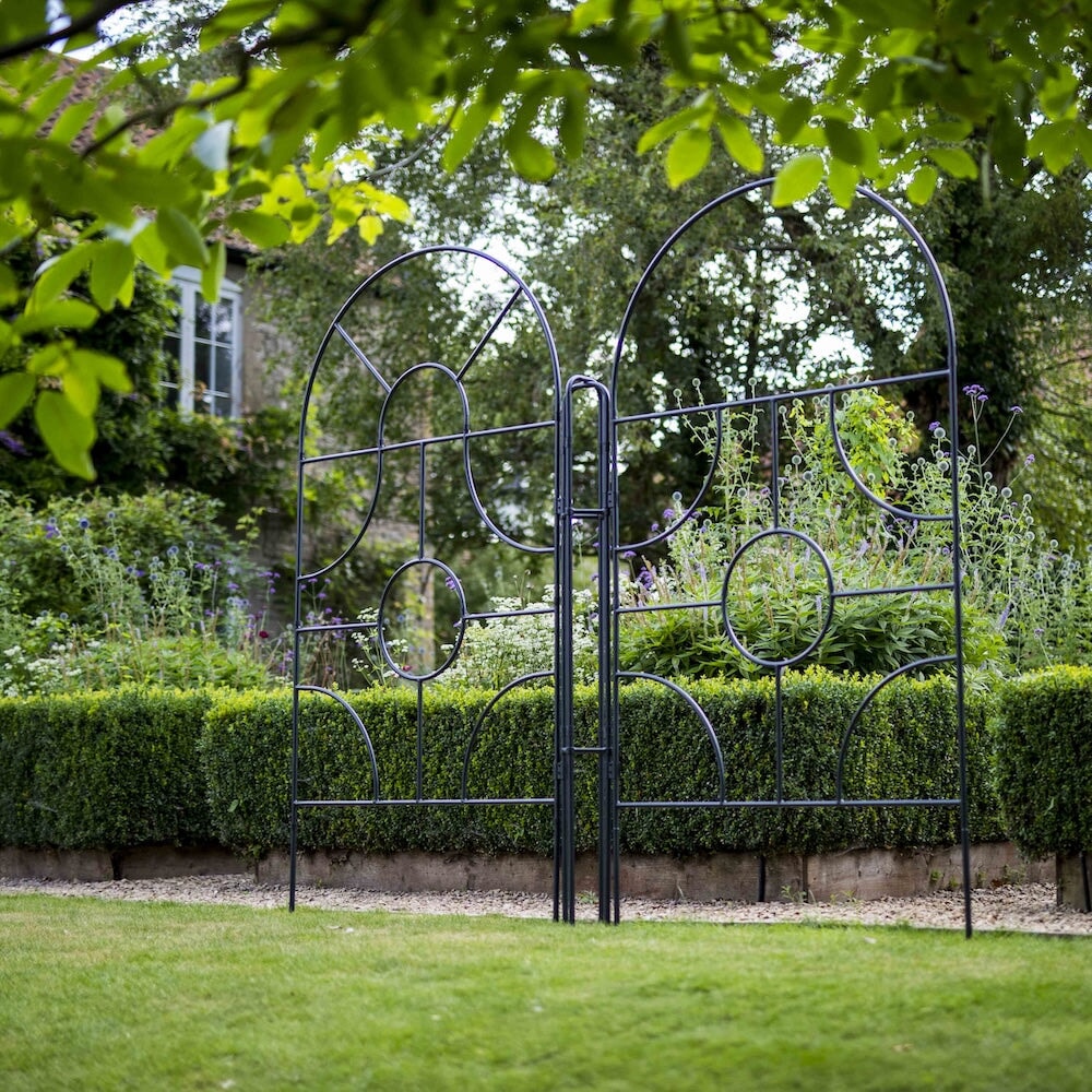 Angled shot of two agriframes georgian round top screens on the edge of a lawn in a large garden scene