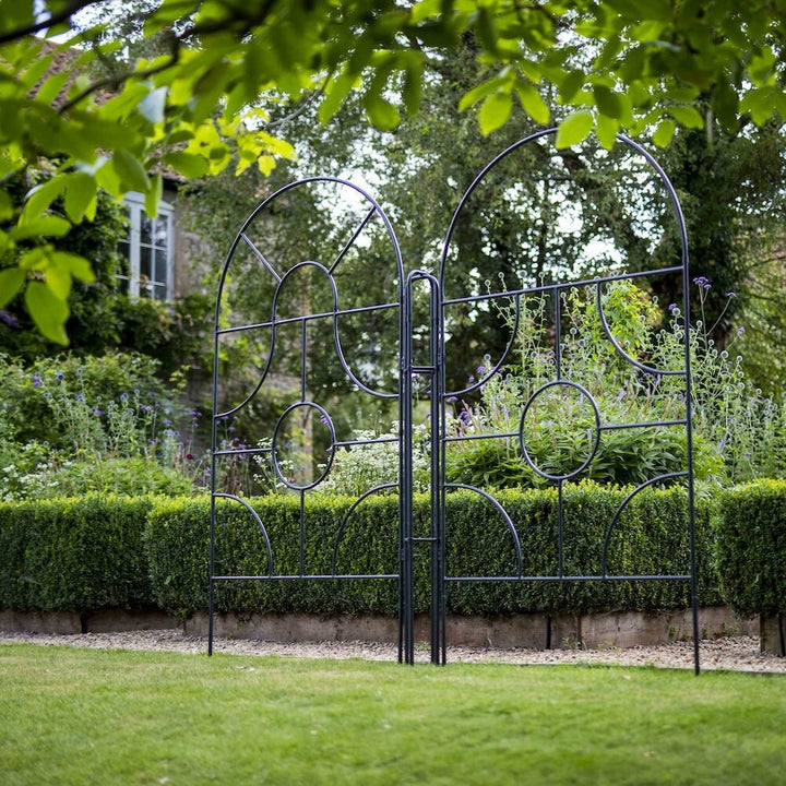 Angled shot of two agriframes georgian round top screens on the edge of a lawn in a large garden scene