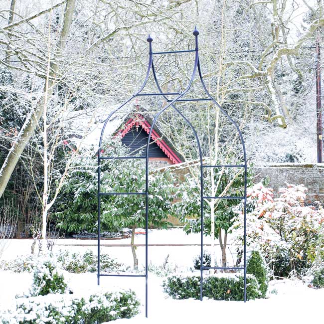 Decorative metal archway in a snowy garden setting