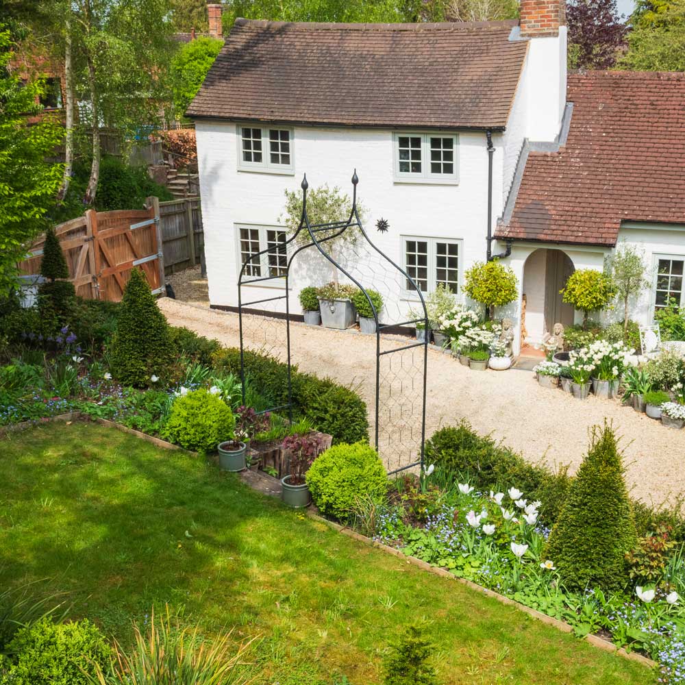 White house with a well-maintained garden featuring various plants and flowers.