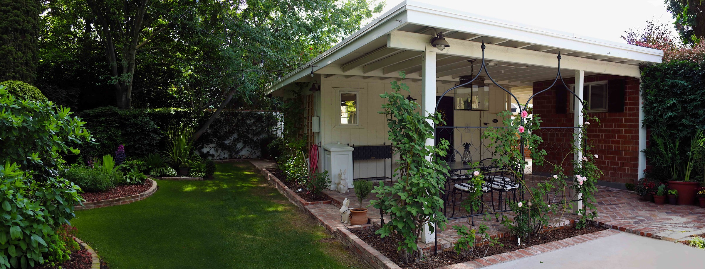 Two Gothic Screens installed in a flowerbed in front of a covered garden patio 