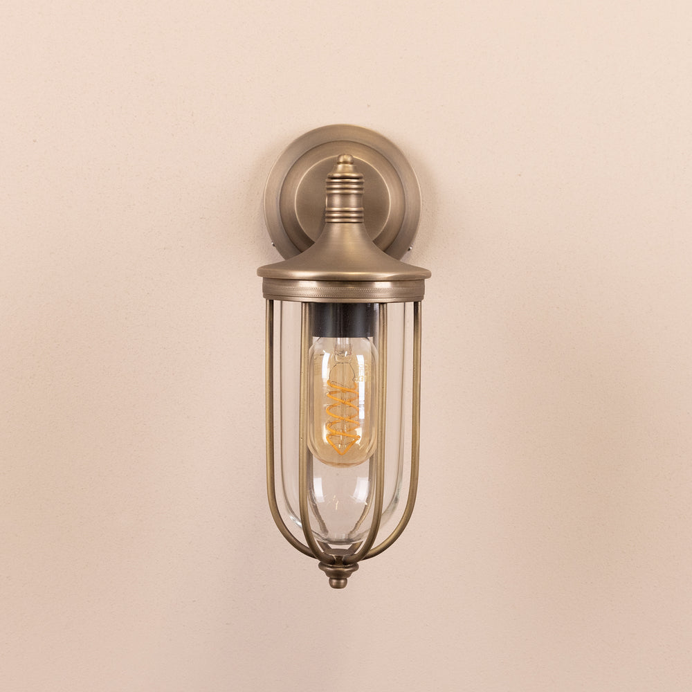Front on image of the Agriframes Outdoor Wall Lamp in a Brass finish with its bulb switched off, mounted on a neutral background. 