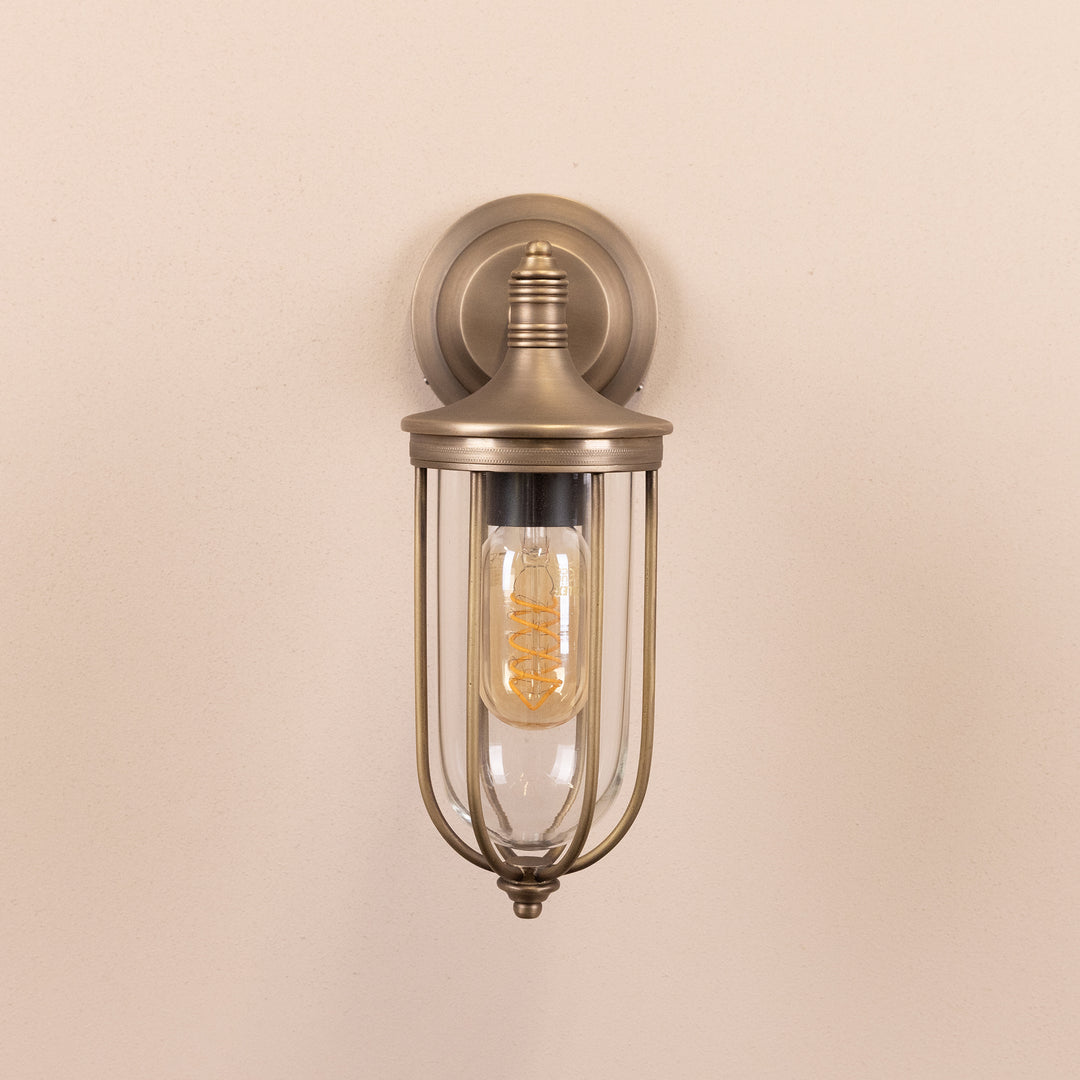 Front on image of the Agriframes Outdoor Wall Lamp in a Brass finish with its bulb switched off, mounted on a neutral background. 