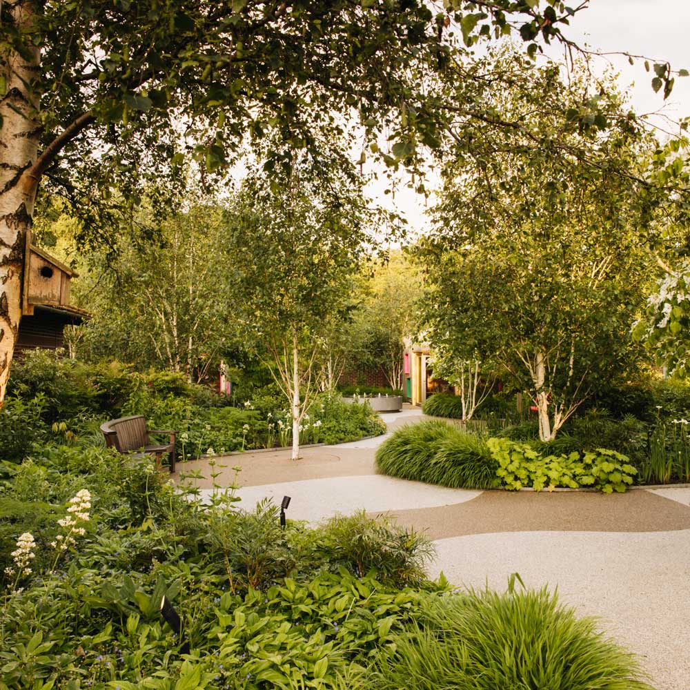 A section of Horatio's Garden, featuring a pathway with vibrant plant beds lining them, and a bench to the side of the path.