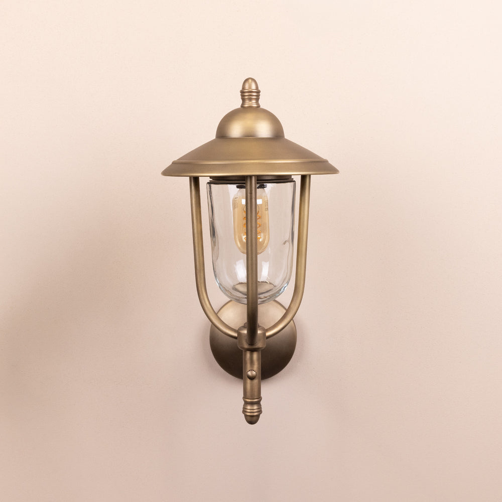 Front on image of the Agriframes Kensington Outdoor Wall Lamp in a Brass finish with its bulb switched off, mounted on a neutral background. 
