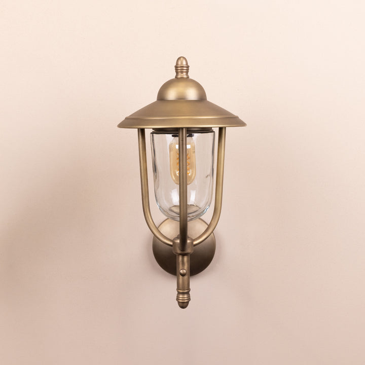 Front on image of the Agriframes Kensington Outdoor Wall Lamp in a Brass finish with its bulb switched off, mounted on a neutral background. 