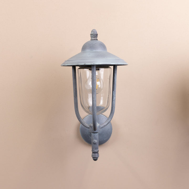 Front on image of the Agriframes Kensington Outdoor Wall Lamp in an Old Iron finish with its bulb switched off, mounted on a neutral background. 