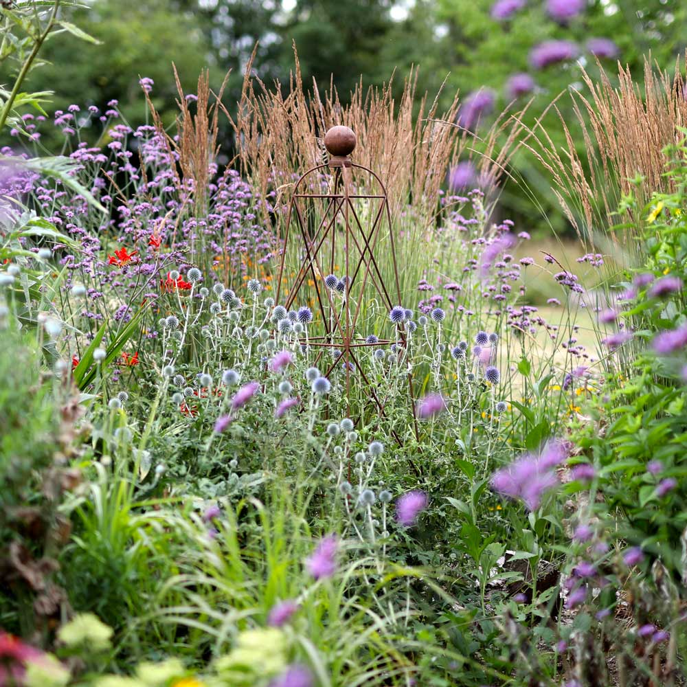 Garden scene with a metal sculpture amidst flowers and grasses
