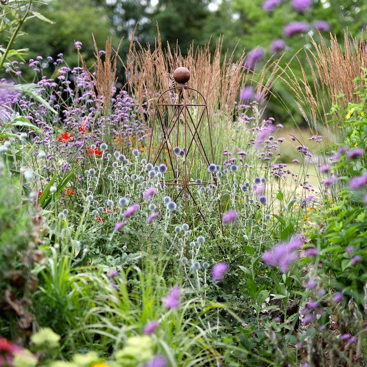 Garden scene with a metal sculpture amidst flowers and grasses