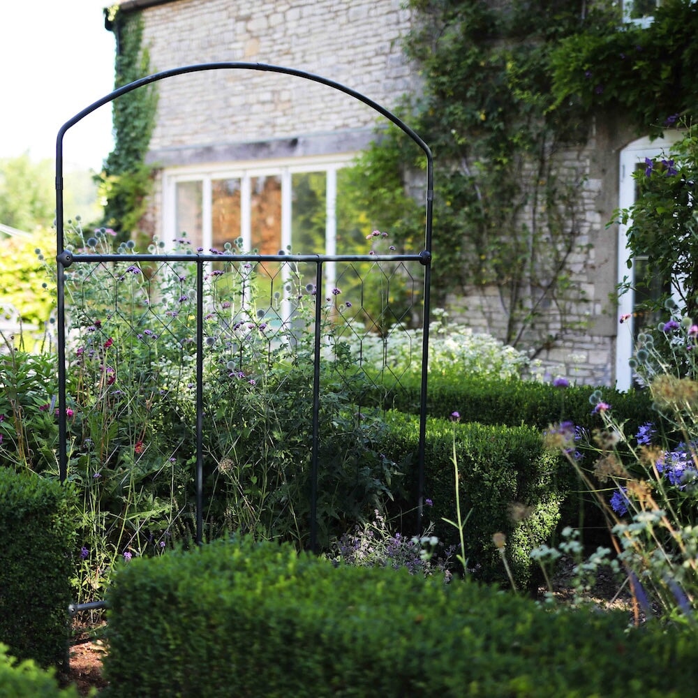 Agriframes monet fencing screen amongst short manicured hedgerows in a flowerbed