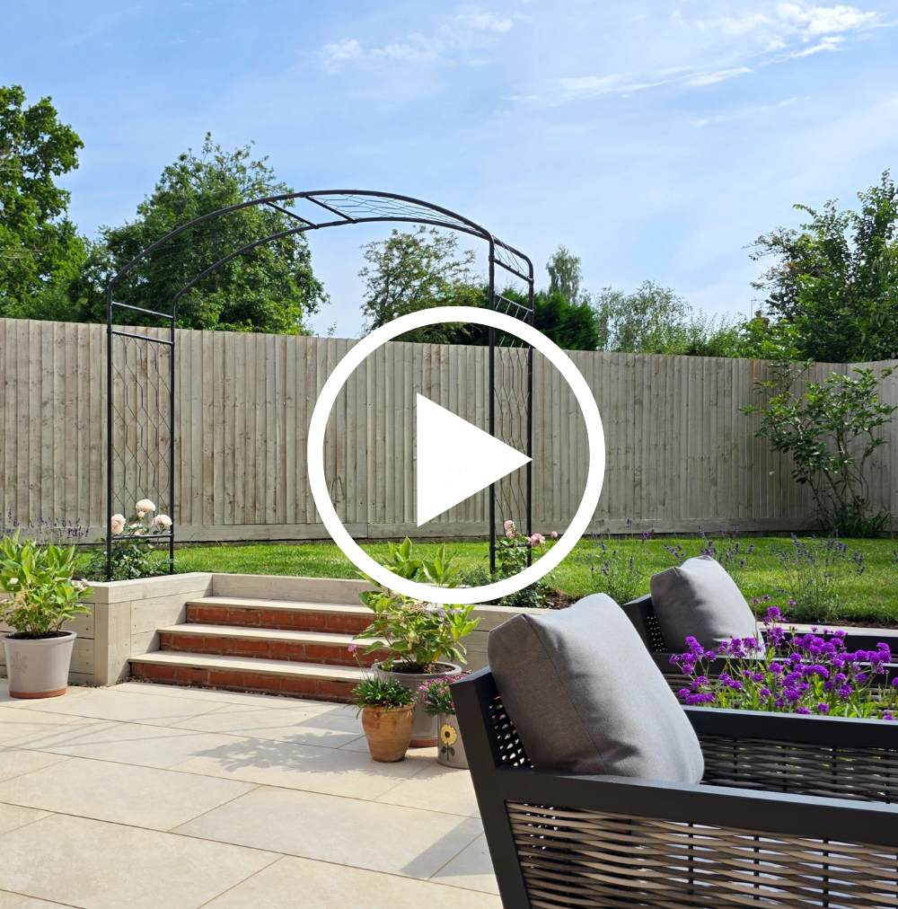 Garden scene with a bench, plants, and a wooden fence under a blue sky.