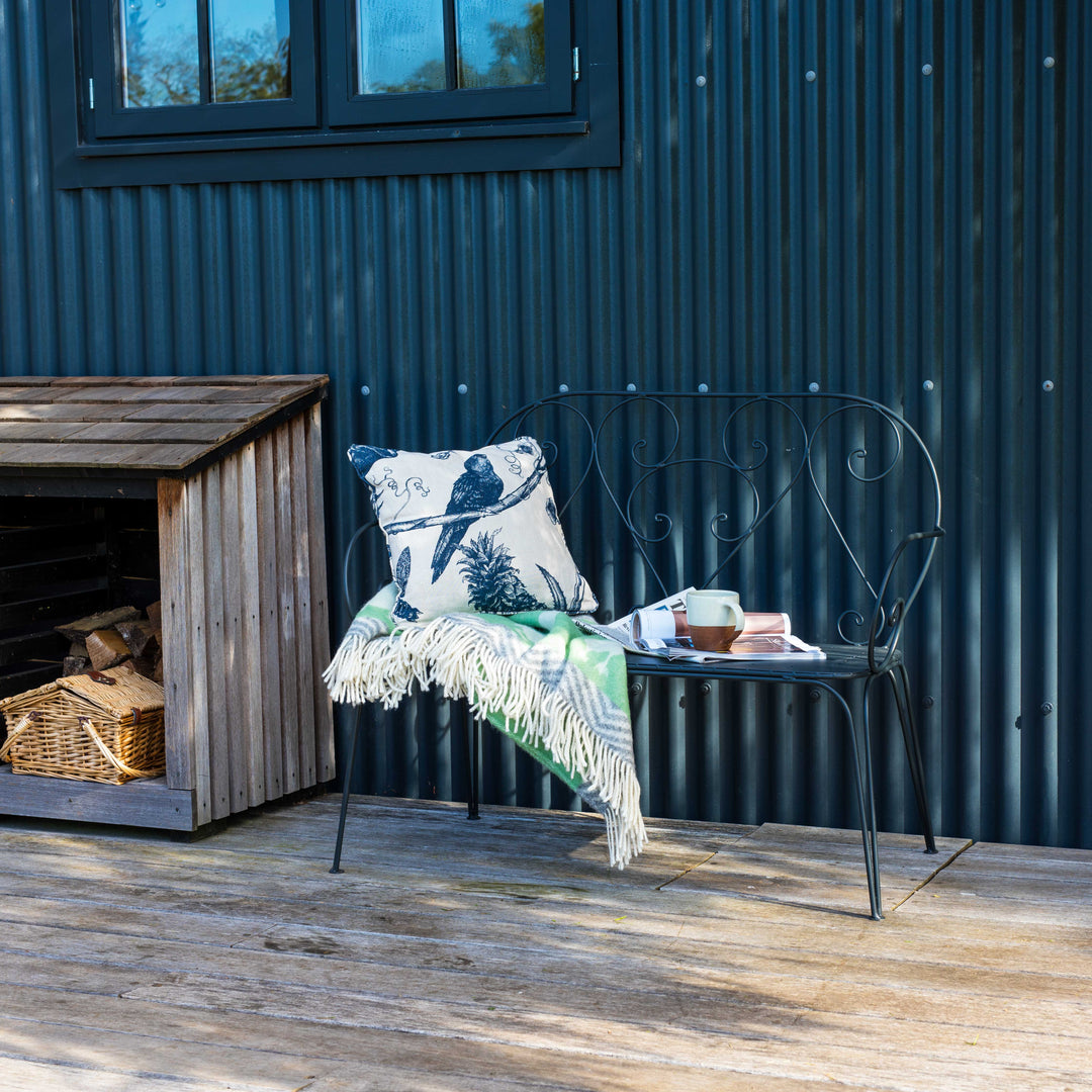 Outdoor seating area with Agriframes Pavillion Vintage Garden Bench and decorative items against a corrugated metal wall.