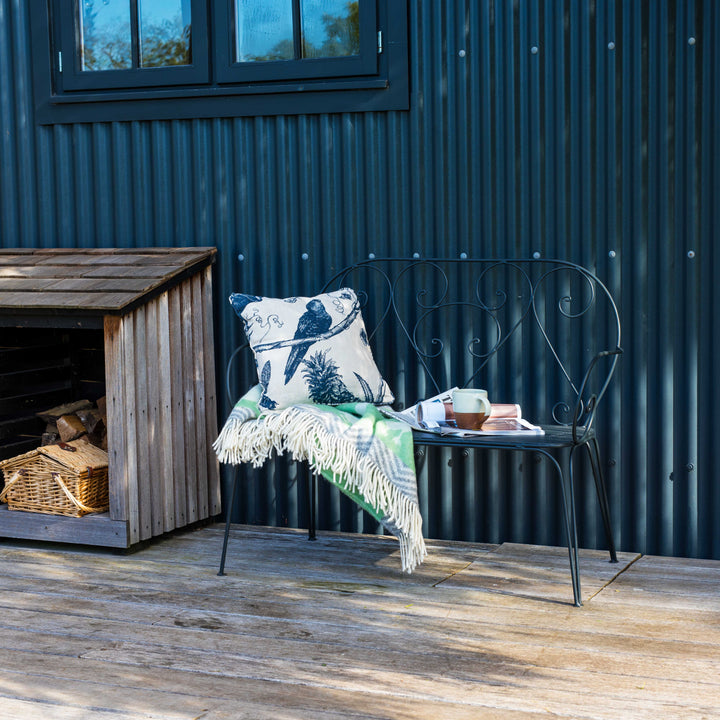 Outdoor seating area with Agriframes Pavillion Vintage Garden Bench and decorative items against a corrugated metal wall.
