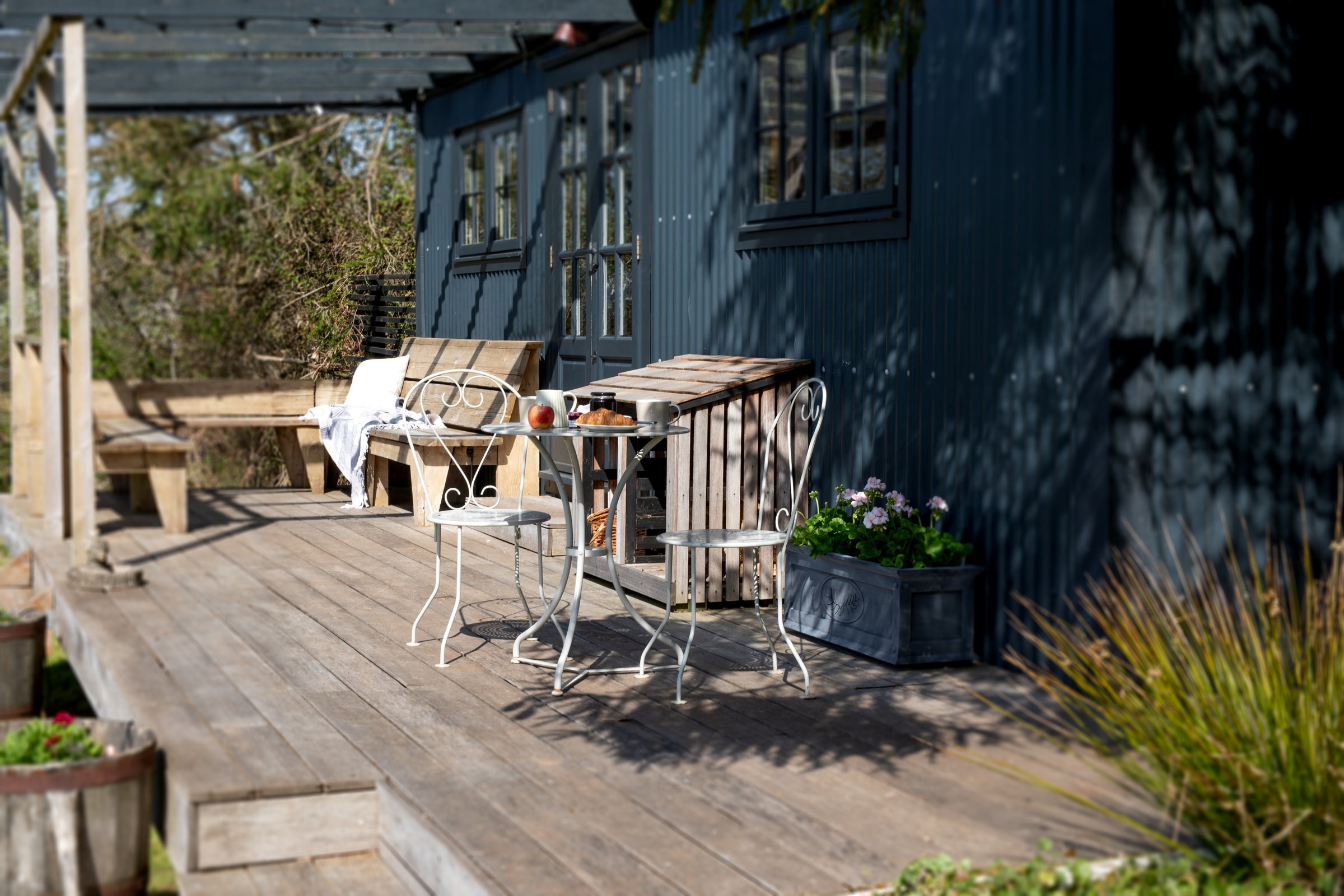 Agriframes Provence Bistro Set on a wooden decking with a breakfast set up on the table. 