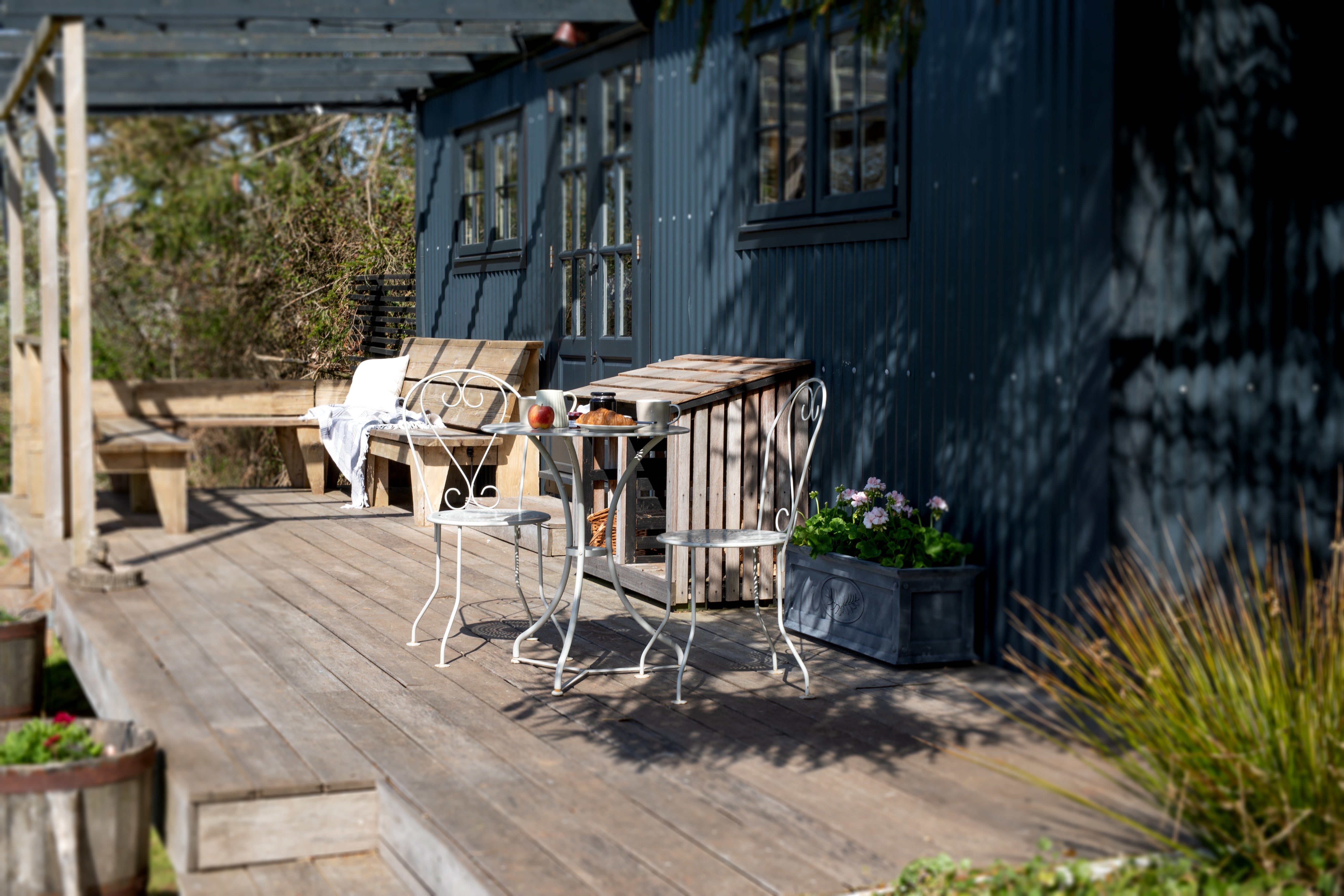 Agriframes Provence Bistro Set on a wooden decking with a breakfast set up on the table. 