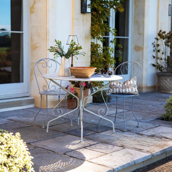 Outdoor patio setting with a Provence Vintage 4 Seat Table Set in front of a building.