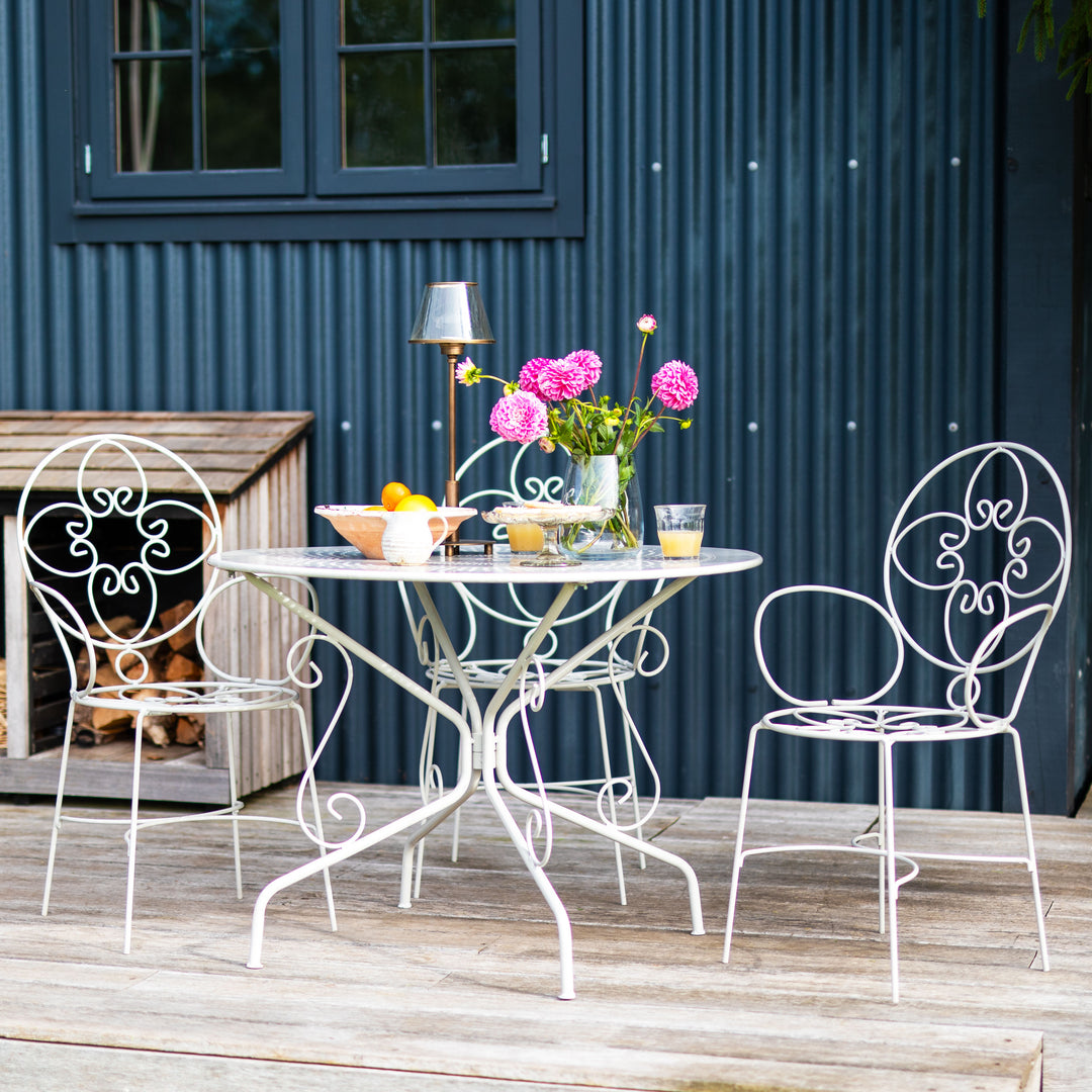 Outdoor patio set with Agriframes Provence Vintage 4 Seater Round Table | metal table and chairs against a blue corrugated metal wall