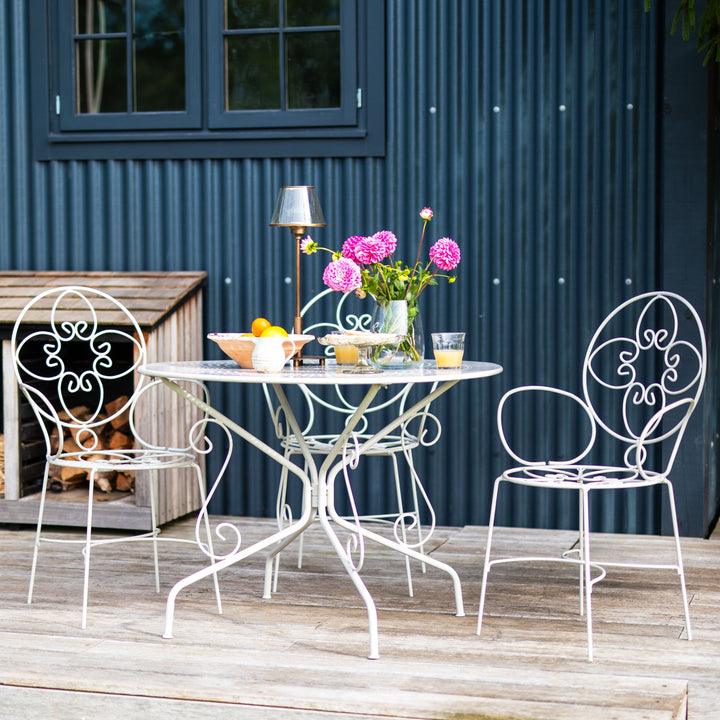 Outdoor patio set with Agriframes Provence Vintage 4 Seater Round Table | metal table and chairs against a blue corrugated metal wall