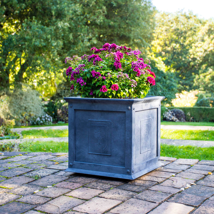 RHS Heritage Zinc Planter with pink flowers on a stone patio