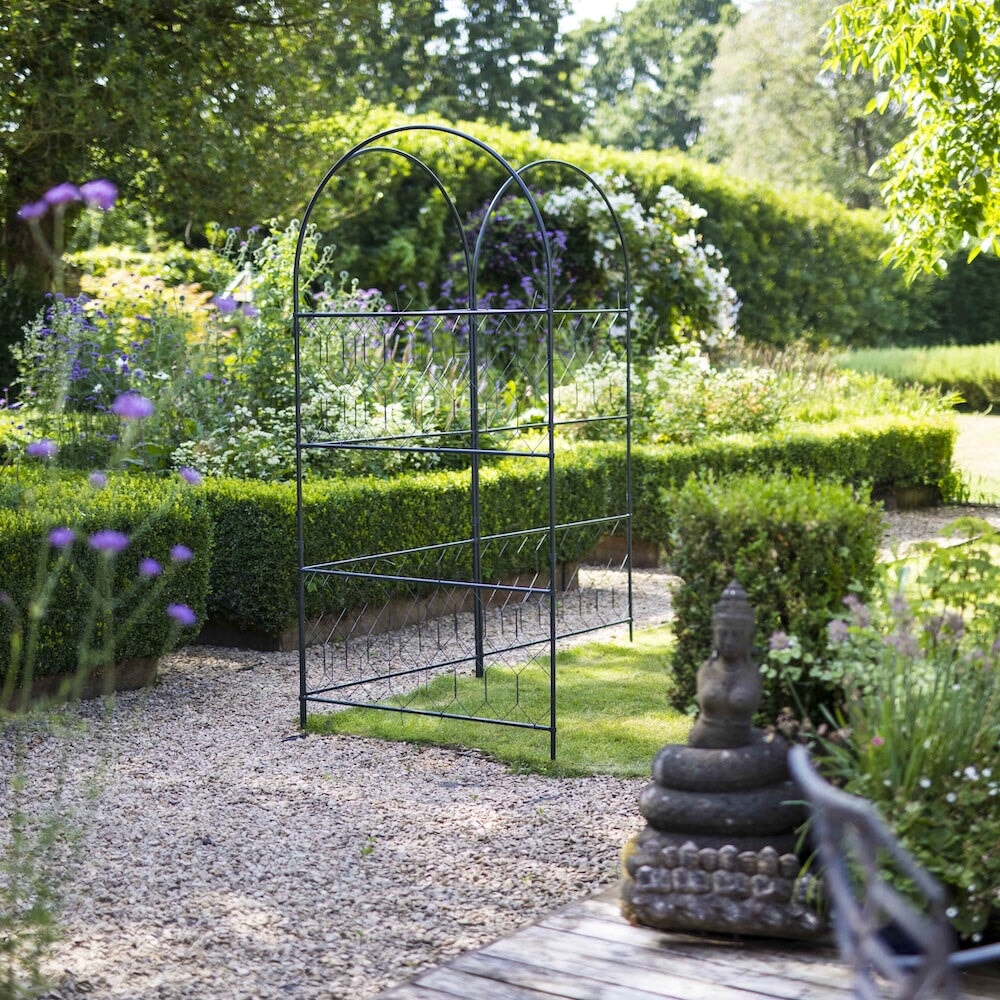 Trio of agriframes versatility screens linked together on the corner of a lawn in a garden scene