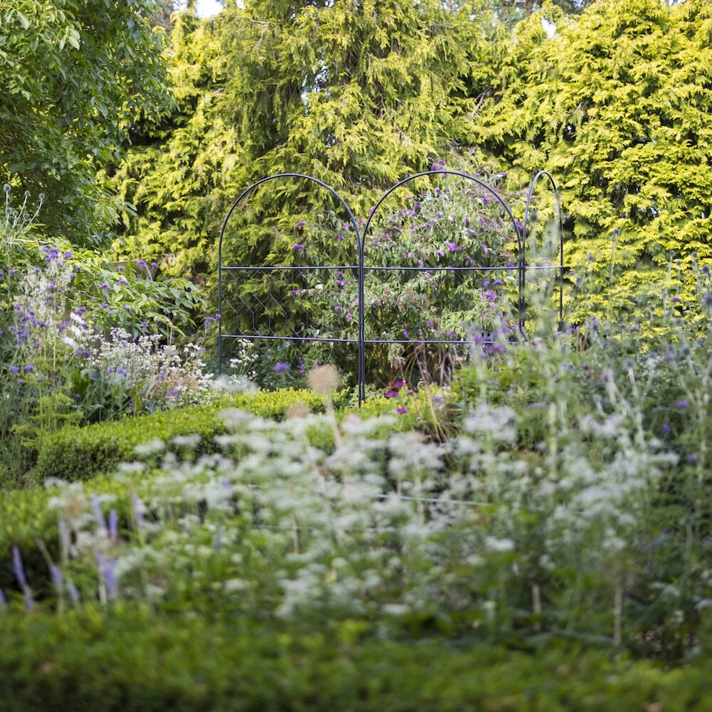 Trio of agriframes versatility screens amongst a large, floral garden 